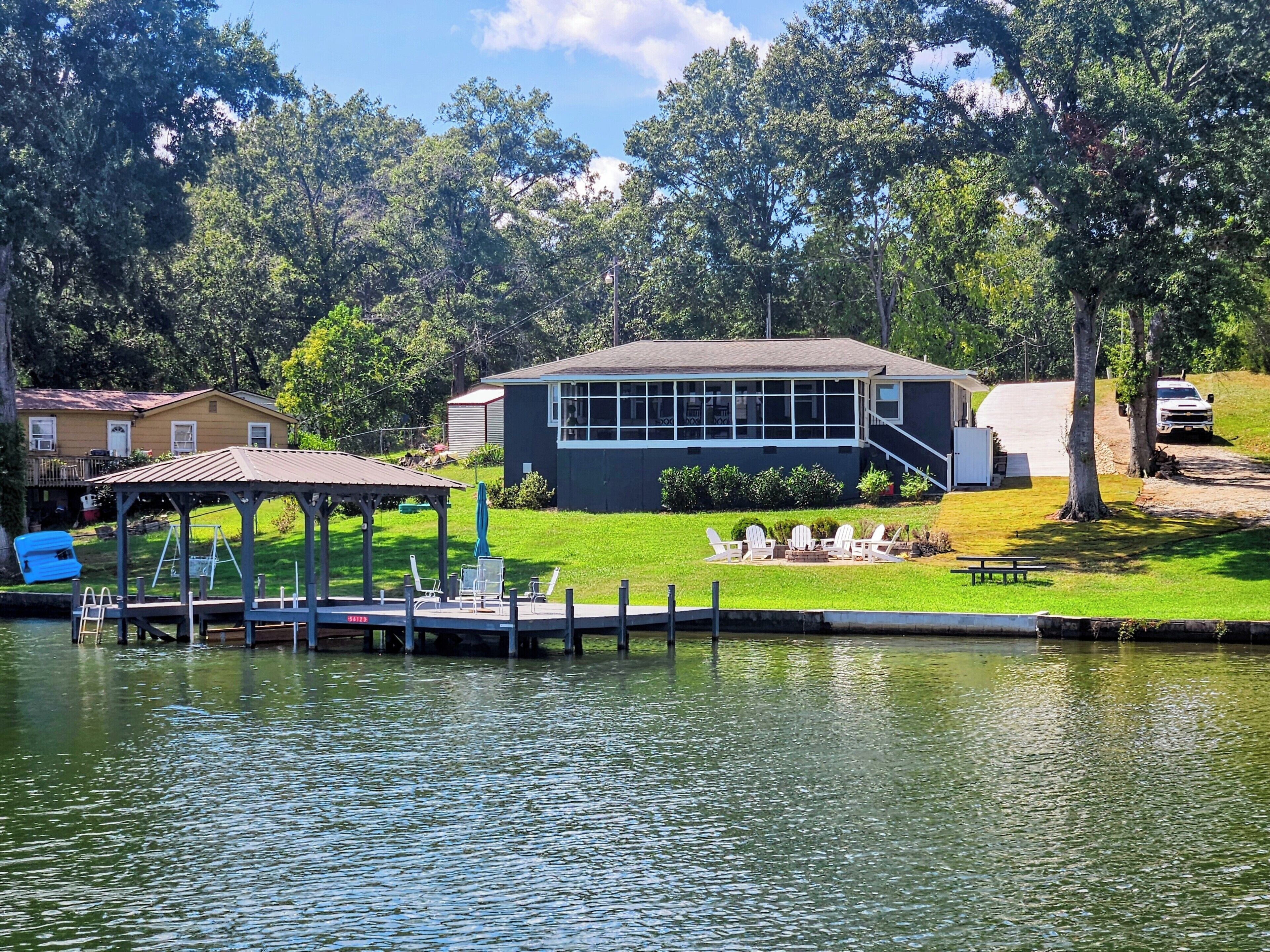 A lakeside property with a dock, a gazebo, and a building with a large window.
