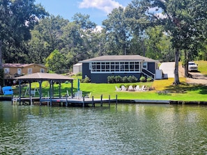 A lakeside property with a dock, a gazebo, and a building with a large window.
