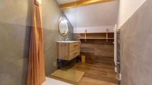 Un baño moderno con tocador de madera, un espejo y zona de ducha.