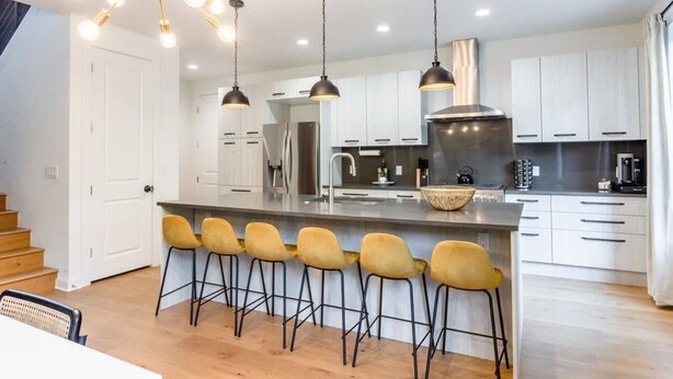 A modern kitchen with a central island, bar stools, pendant lights, and stainless steel appliances. - Eastside House Supreme 6 Min Drive to DT (Austin)