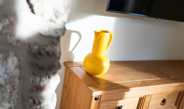 A wooden cabinet with a yellow vase and a white mug.