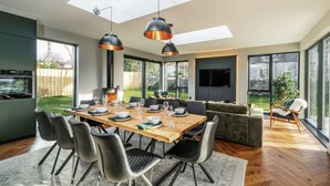 A modern kitchen with a dining area, large windows, and a cozy seating area. - Blythewood Holiday Home (Kemnay)