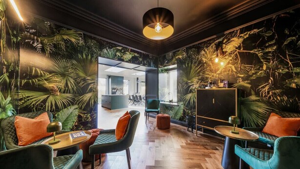A modern interior with a cozy seating area, a large mirror, and a wall with a tropical mural. - Blythewood Holiday Home (Kemnay)