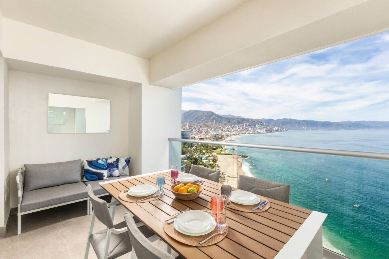 Un balcón con una mesa dispuesta para dos personas, con vista al mar.