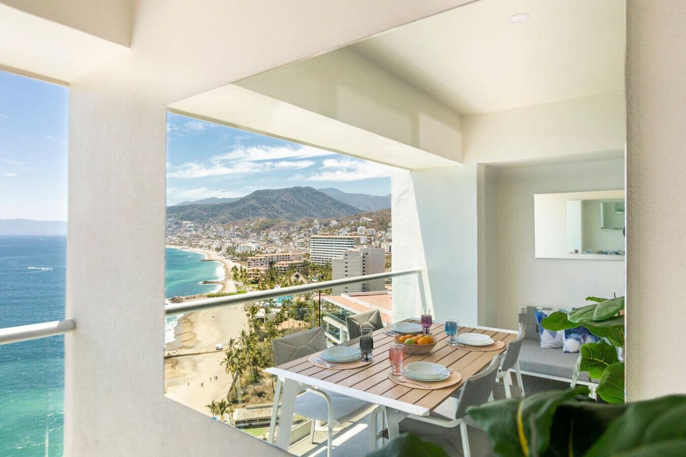 En balkon med et spisebord, med udsigt over en strand og hav.