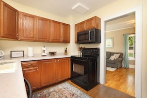 A kitchen with wooden cabinets, a microwave, and a stove.