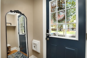 A dark blue door with a white window, a doorbell, and a wall-mounted intercom.