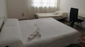 A hotel room with two beds, a desk, and a chair.