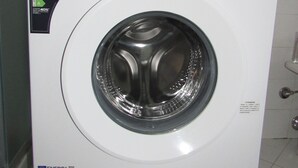 A front-loading washing machine with a control panel, energy efficiency label, and a door with a handle.
