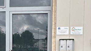 A glass door with a metal handle, a parking lot with cars, and two signs on the wall indicating room information.
