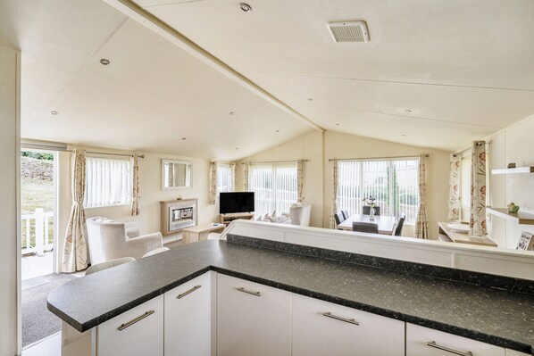 A spacious living area with a large TV, a fireplace, and a dining table. - 2 Bed Caravan - Sleeps 6 - Pets - Pool - Parking (Newquay)