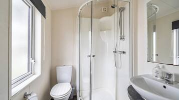 A modern bathroom with a glass-enclosed shower, a white toilet, and a sink with a marble countertop.