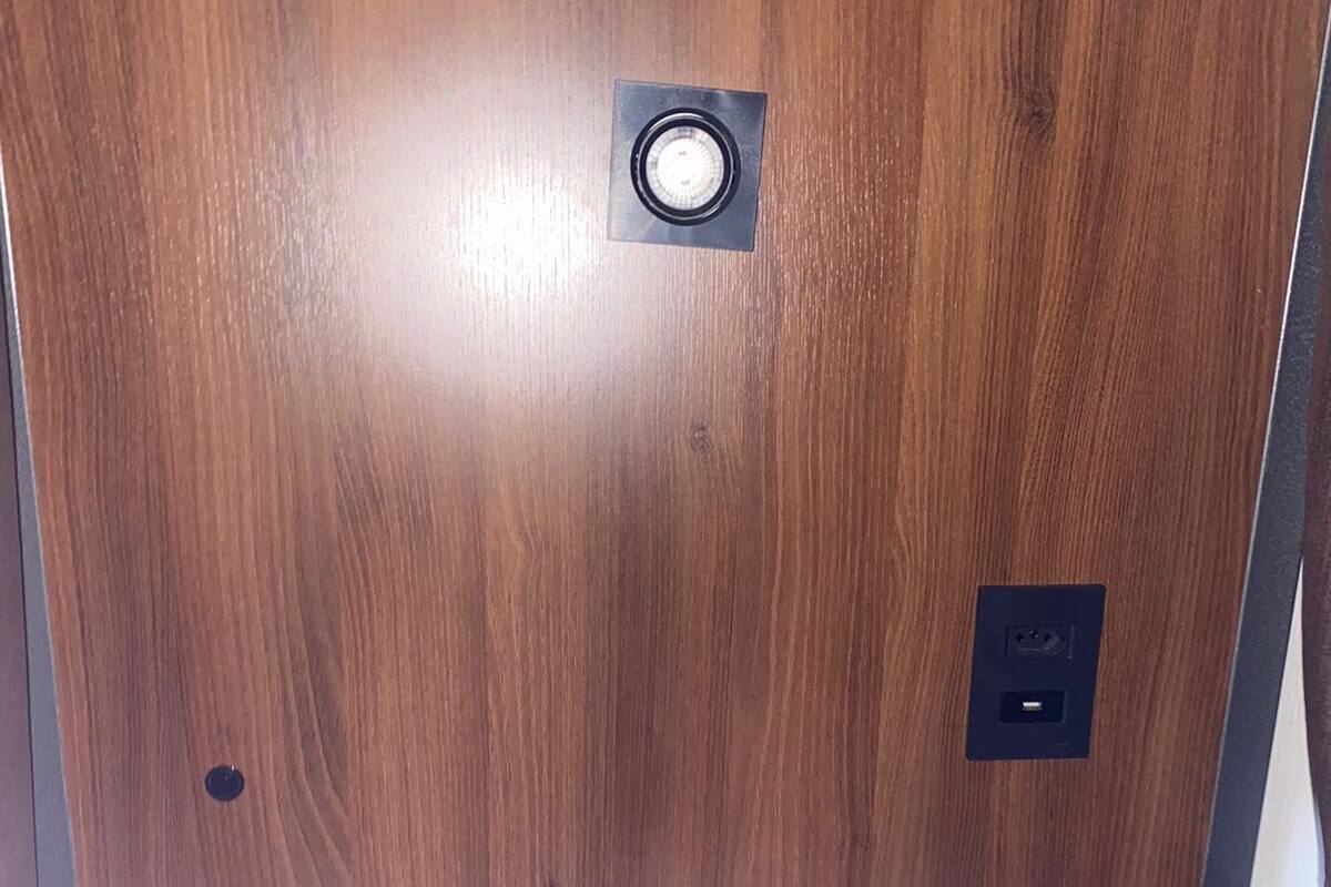 Un soffitto in legno con un lampadario e una presa di corrente.