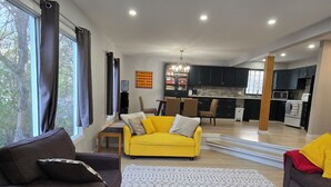 A modern living room with a yellow sofa, dark armchairs, and a patterned rug.