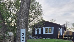 A house with a number sign '230' attached to a tree, a grassy yard, and a wooden deck.