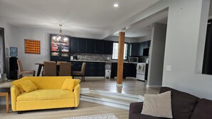 A modern living room with a yellow sofa, a brown sofa, and a patterned rug.