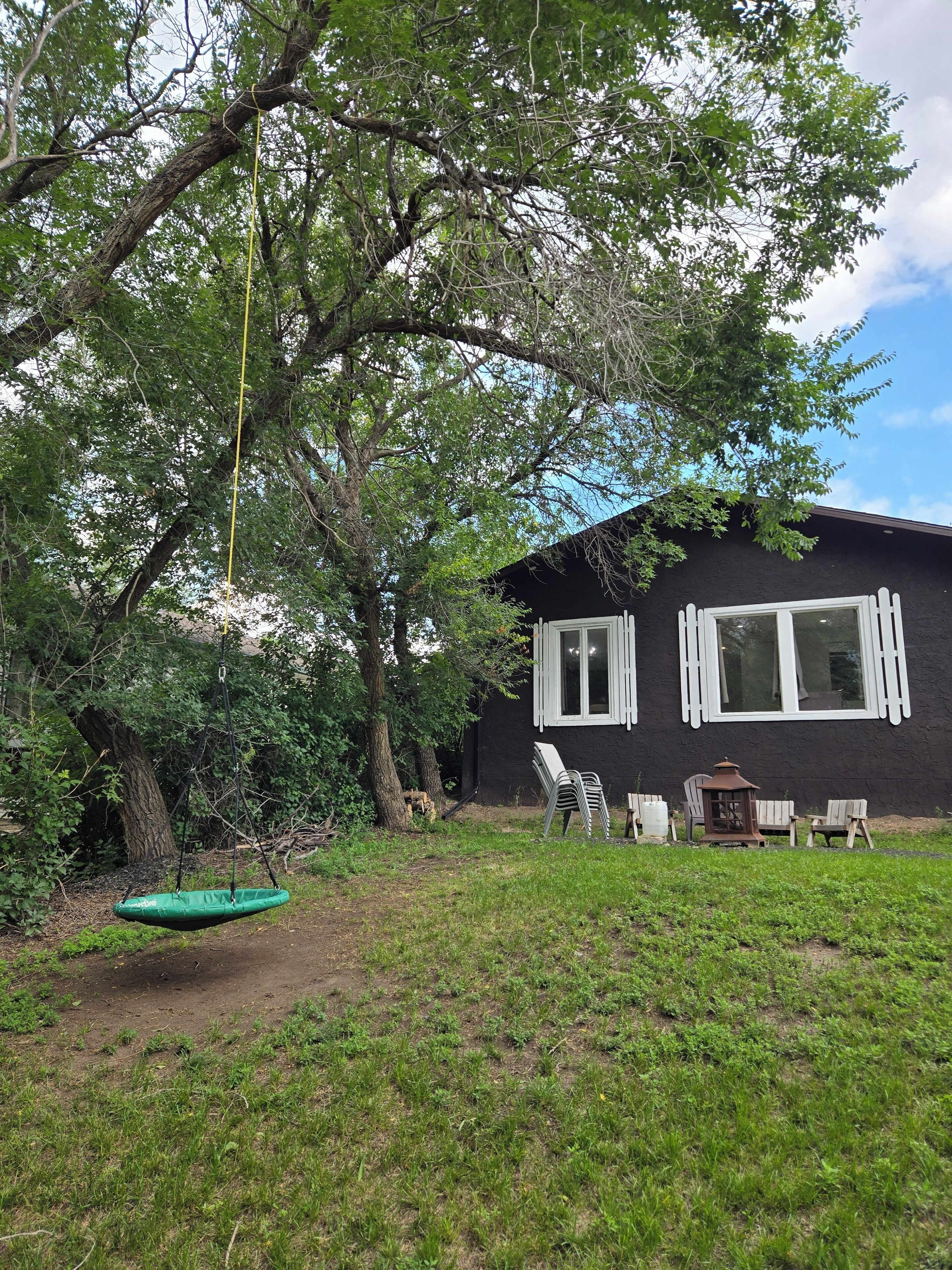 Una casa con un'altalena, sedie da giardino e un tavolino.