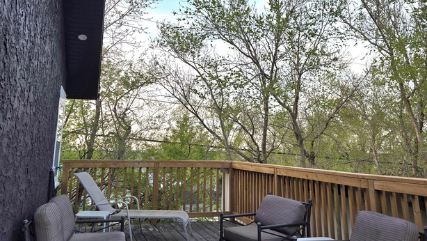 A deck with outdoor furniture, including chairs and a table, surrounded by trees.