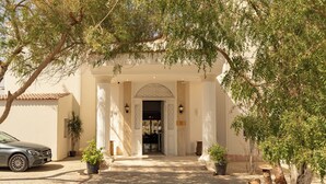 A building entrance with a paved driveway, potted plants, and a parked car. - Noya By Dhara Hotels (Giza)