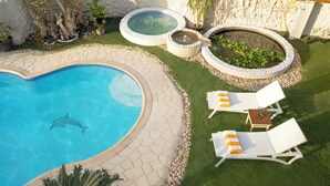 A swimming pool with a dolphin, surrounded by lounge chairs and hot tubs. - Noya By Dhara Hotels (Giza)