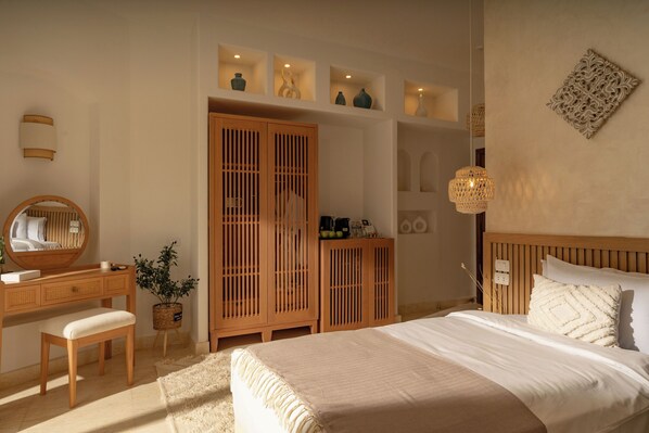 A bedroom with a bed, wooden wardrobe, bedside table, and a mirror.