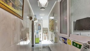 A hotel corridor with a chandelier, glass doors, and a trash bin. - Thema Motel (Seoul)
