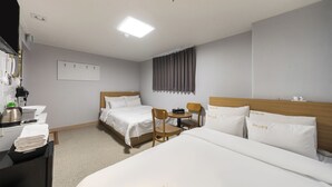 A hotel room with a bed, a desk with a kettle, a chair, and a small table. - Thema Motel (Seoul)