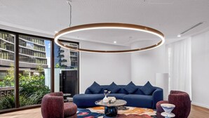 A modern living room with a blue sofa, a colorful rug, and a unique coffee table.