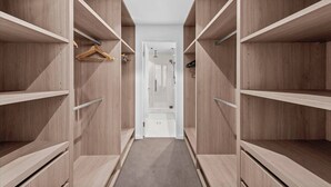 A walk-in closet with open shelving and a door leading to a bathroom.