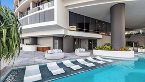 A modern hotel with a pool area, including lounge chairs and a seating area.