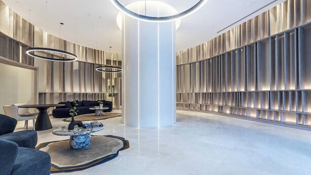 A modern lobby with a central column, seating area, and a patterned wall.
