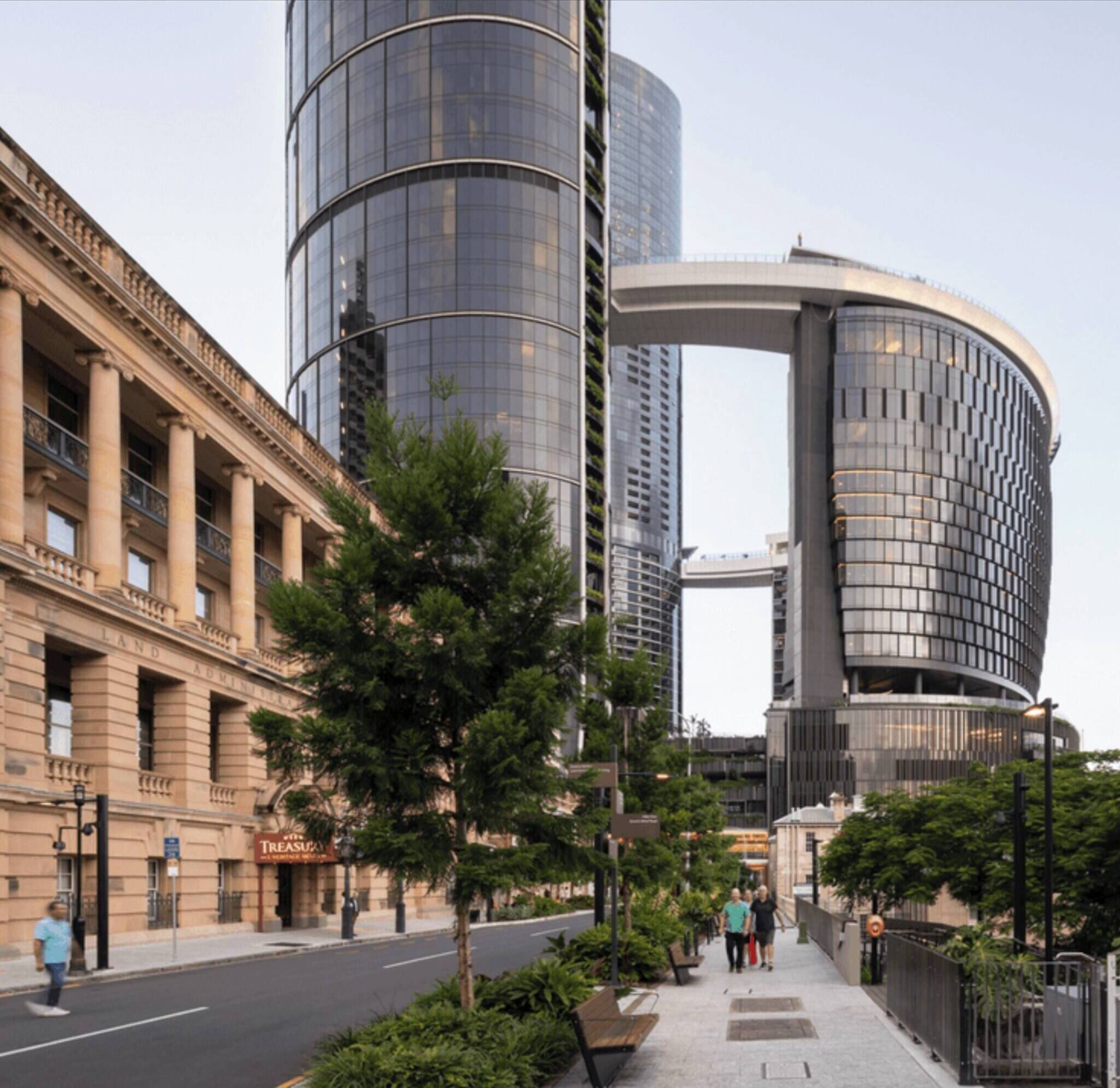 A modern building with a curved glass facade, adjacent to a classical building with columns.