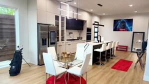 A modern kitchen with a central island, white bar stools, and a red rug. - Trinity Two Luxury Home (Dallas)