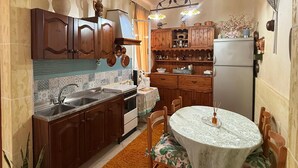 Cocina compacta con armarios de madera, horno empotrado y comedor con mesa y sillas.