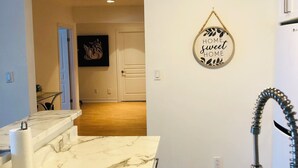 Une cuisine dotée d’un plan de travail en marbre, d’un évier avec un robinet flexible et d’un élément décoratif mural.