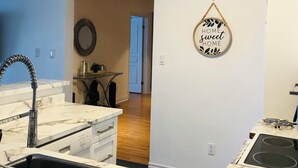 Une cuisine moderne avec des plans de travail en marbre, un évier encastré et une cuisinière. Un miroir est accroché au mur et une porte donne accès à une autre pièce.