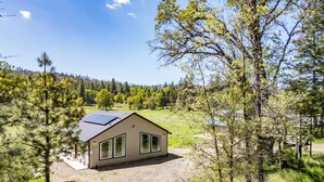 Una casa moderna con techo de paneles solares, rodeada por un bosque y un lago.