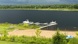 A lakeside dock with boats, a sandy beach, and a forested shoreline.