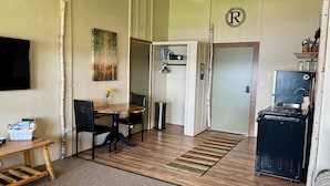 A compact kitchen with a dining area, a small table with chairs, a stove, and a refrigerator.