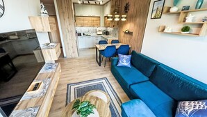 Een moderne woonkamer met een blauwe bank, een houten salontafel en een eethoek met blauwe stoelen.