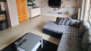 Una sala moderna con sofá, mesa de centro, televisor y chimenea.