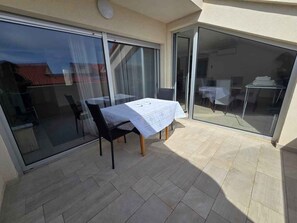 A balcony with a table and chairs, a sliding glass door, and a tiled floor. - Holiday flat with air conditioning (Medulin)