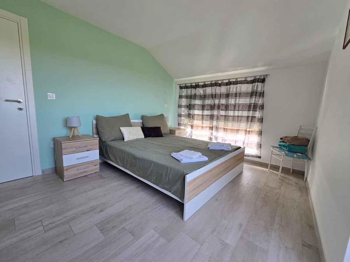 Une chambre à coucher avec un lit, une table de chevet et une fenêtre avec des rideaux.