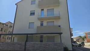 En byggnad med flera våningar, balkonger, en parkeringsplats och en klar himmel.
