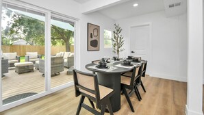 A dining area with a round table, black chairs, and a view of the outdoor patio. - Media Room & Patio - Downtown View- 4 Bedrooms (Houston)