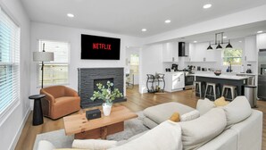 A modern living room with a fireplace, a sofa, a coffee table, and a TV mounted on the wall. - Media Room & Patio - Downtown View- 4 Bedrooms (Houston)