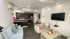A modern living room with a sofa, a coffee table, and a TV. - APARTAMENTO VISTA MARE 14-101 (Samana)