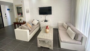 A modern living room with a sofa, a coffee table, and a TV mounted on the wall. - APARTAMENTO VISTA MARE 14-101 (Samana)