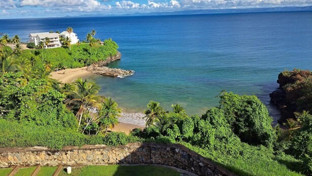 A coastal property with a beach, lush greenery, and a view of the ocean. - APARTAMENTO VISTA MARE 14-101 (Samana)