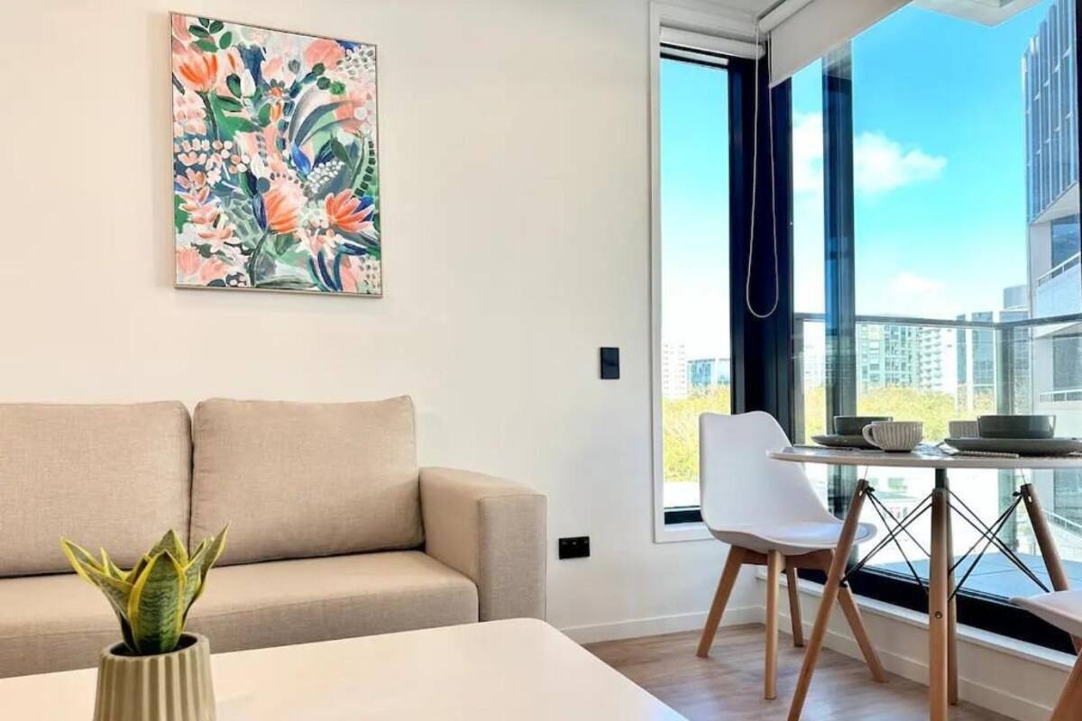 Una sala moderna con un sofá, una mesa de comedor y una planta en maceta.
